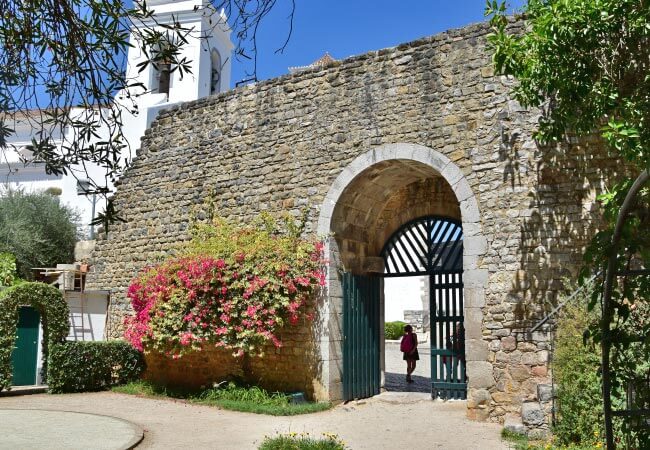 Stone walls and entry arch leading into the historic Moorish castle ruins in Tavira old town