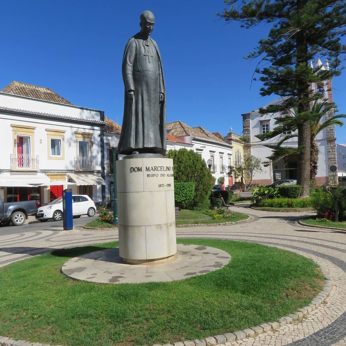 The prominent stone monument statue of Marcelino Franco erected in a public square garden setting surrounded by historic town architecture in Tavira